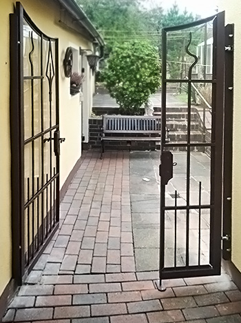 Geschmiedetes Eingangstor nach eigenem Entwurf, in Stahl verzinkt und lackiert, hinterlegt mit Makrolonglas.