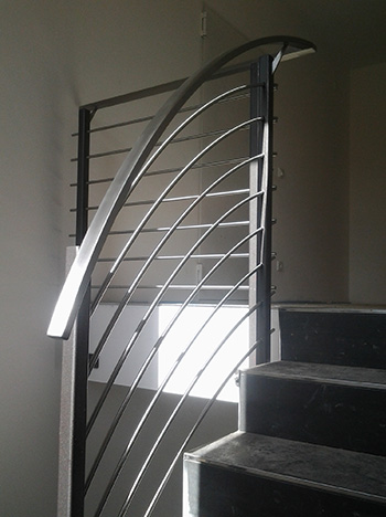 Gerundetes Treppengeländer an einer halbgewendelten Treppe, Edelstahl und lackierter Stahl.